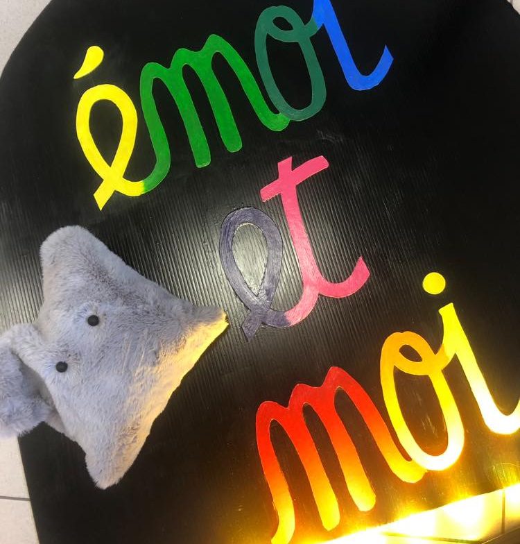 Texte coloré "émoi et moi" avec une peluche gris en forme d'éléphant.